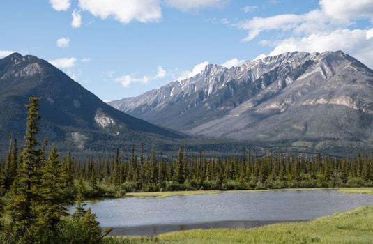 Scenic view of Alberta's Rocky Mountains with lake and forest.