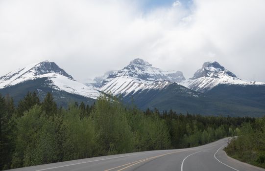 Clouds over Mountains and Road in Forest