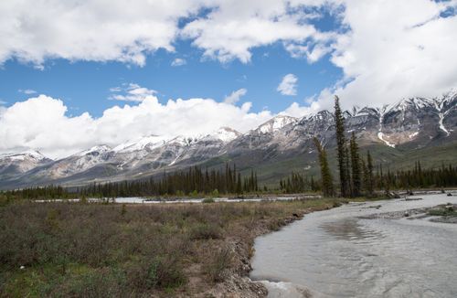 Free Scenic view of snowcapped mountains with a winding river and forested landscape under a blue sky. Stock Photo