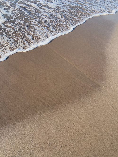 Free Peaceful beach scene with gentle waves lapping on the sandy shore, capturing the essence of coastal tranquility. Stock Photo
