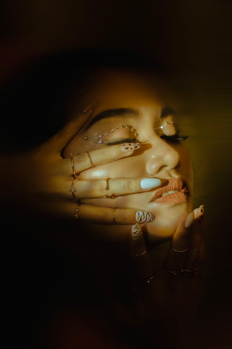 Close-up Of Woman Showing Nails Design On Face