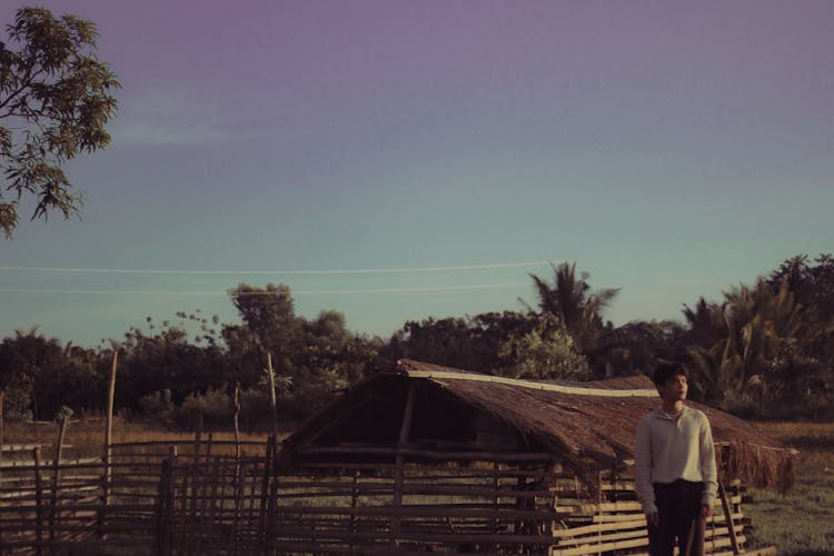 Man In White Long Sleeve Shirt Standing Near Wooden Fence