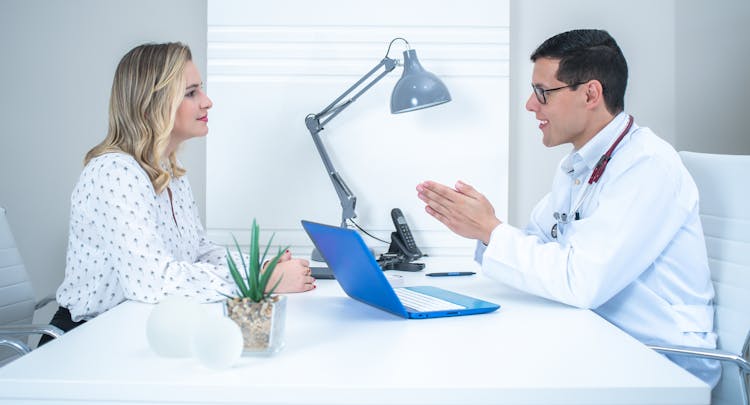 Doctor Talking With Woman In White Long Sleeve Shirt