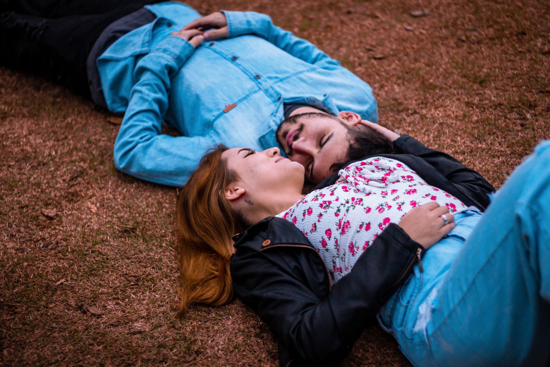 A young couple lying together on grass, enjoying a peaceful moment outdoors.