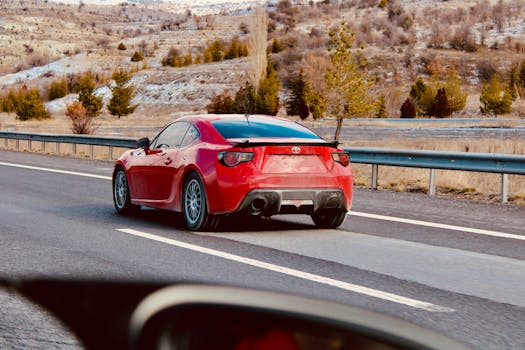 Red sports car cruising on a highway amidst Turkey's scenic, snowy terrain.