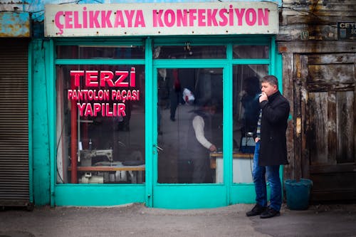 A Man Smoking Outside a Tailoring Store