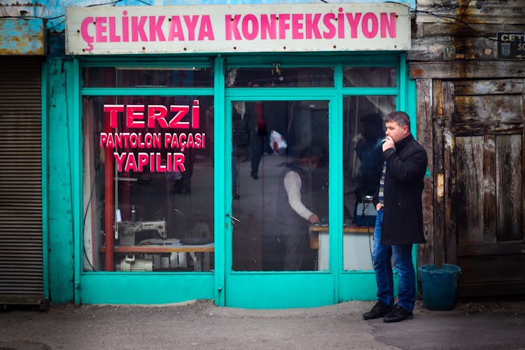 A Man Smoking Outside A Tailoring Store