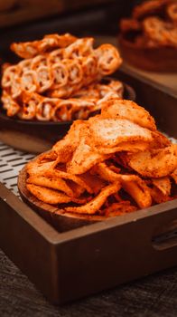 Delicious close-up of spicy Indonesian chips and spiral snacks on a wooden platter. Perfect for culinary imagery. - Fotografer Sidoarjo
