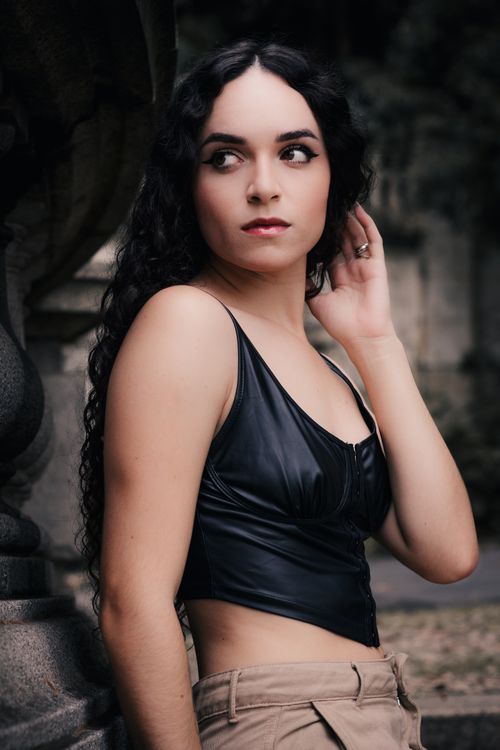 Free A stylish woman with long hair posing outdoors in a black top and beige pants. Stock Photo