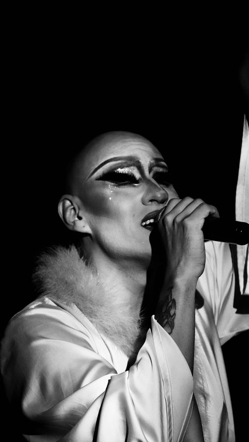 Free Striking monochrome image of a drag queen passionately singing into a microphone. Stock Photo