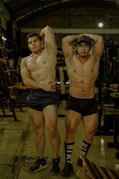 Two muscular men showcasing physique at gym, highlighting strength and fitness.