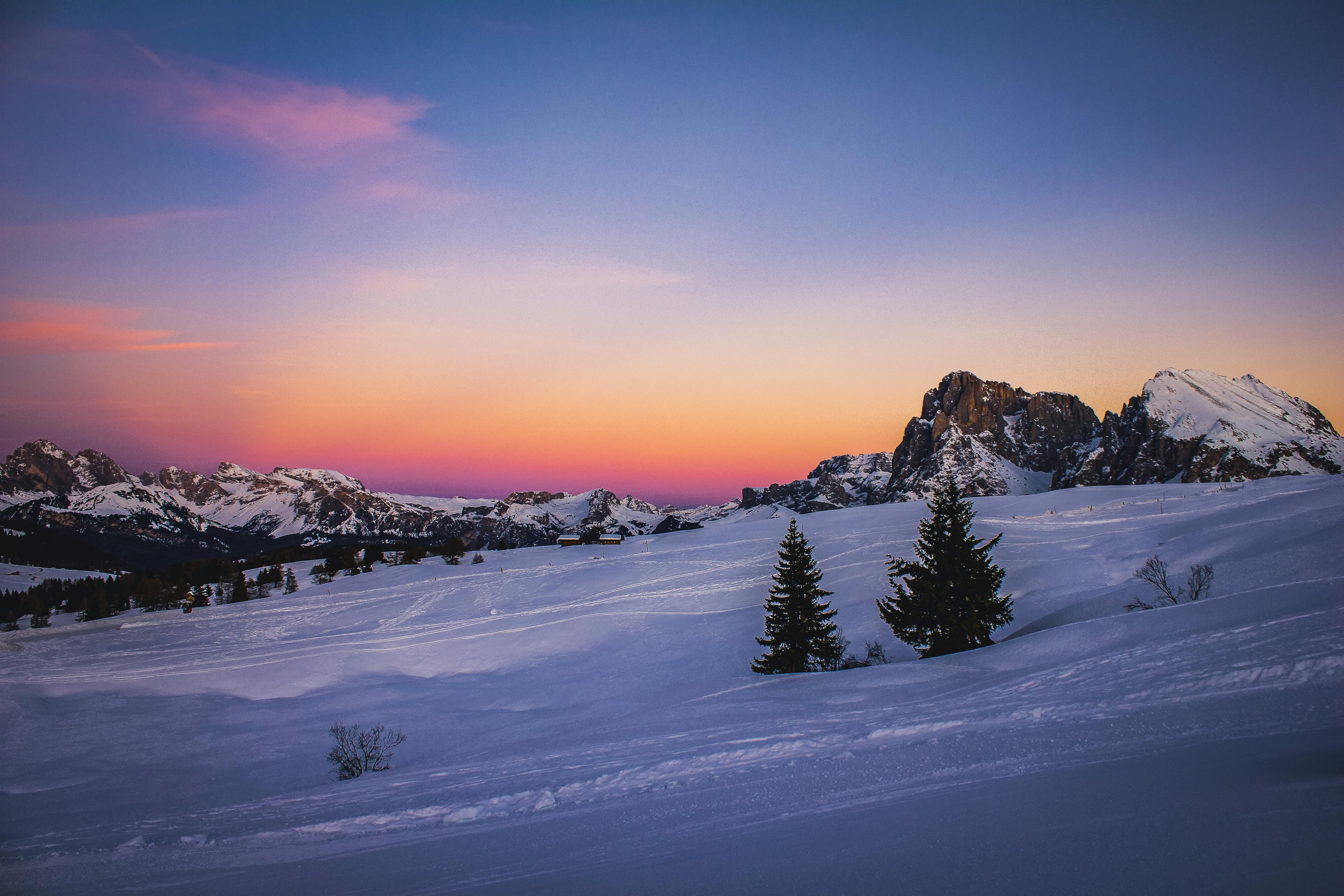 Breathtaking winter sunset over snow-covered mountains and trees, creating a peaceful and serene scene.