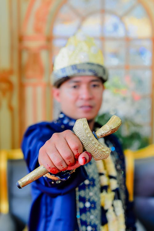 Man in Traditional Clothing Holding Golden Item