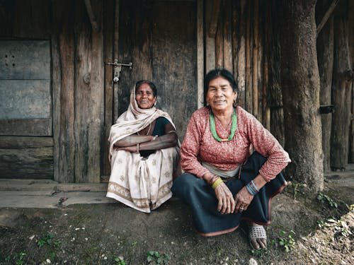 Old Women in Traditional Clothes Sitting near Wooden House