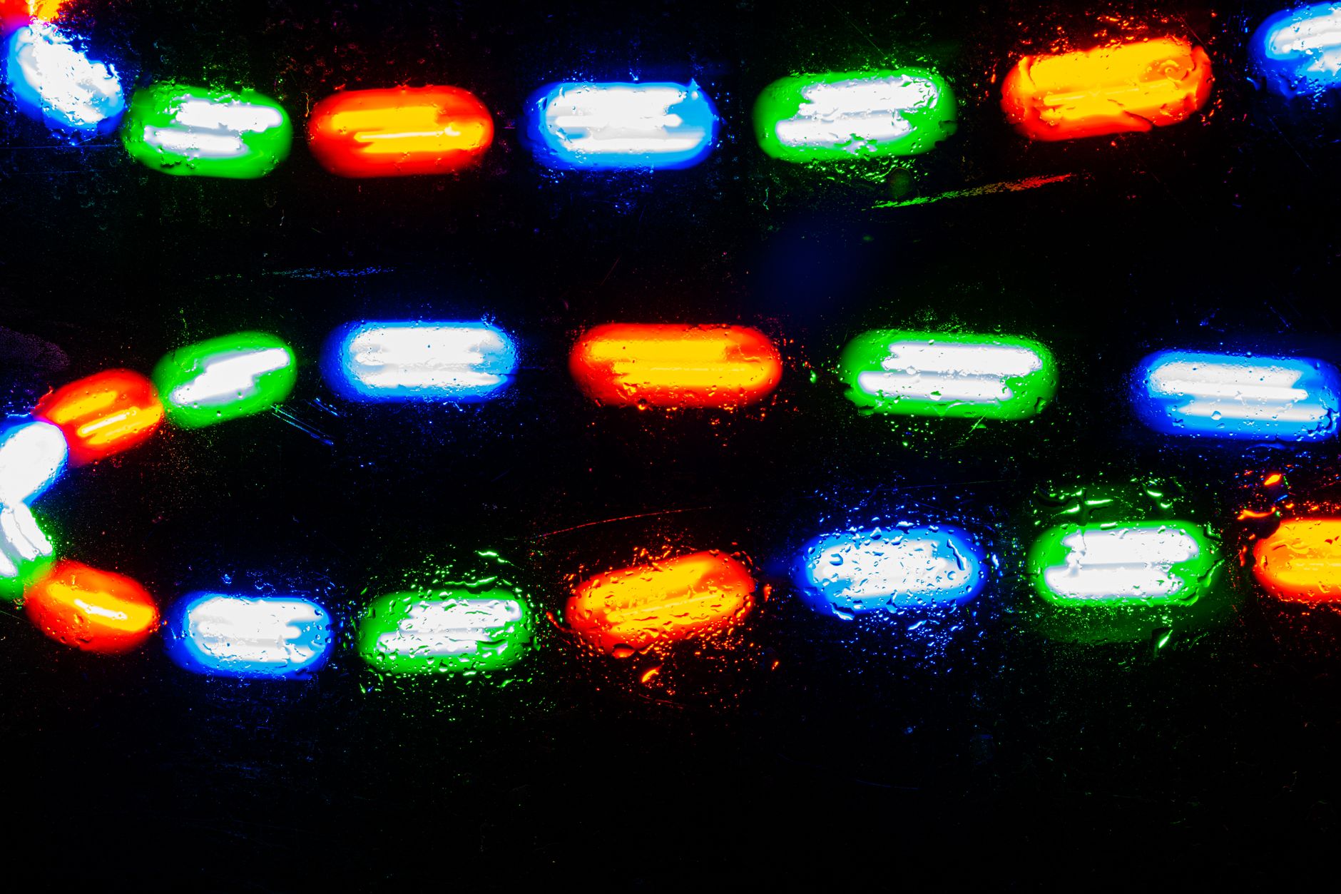 Dynamic close-up of colorful neon lights reflected on a wet surface at night.