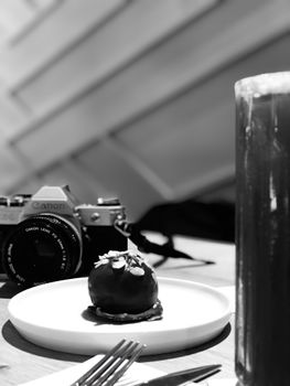 Monochrome photo of a chocolate dessert paired with a vintage camera, embodying classic elegance.