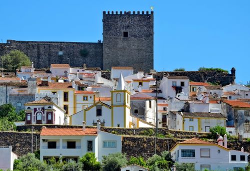 Free Picturesque view of a medieval town with a fortress and vibrant church under a clear blue sky. Stock Photo