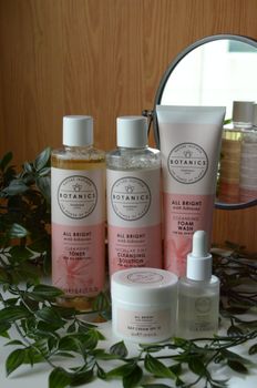 Botanic skincare products with natural leaves and mirror reflection.