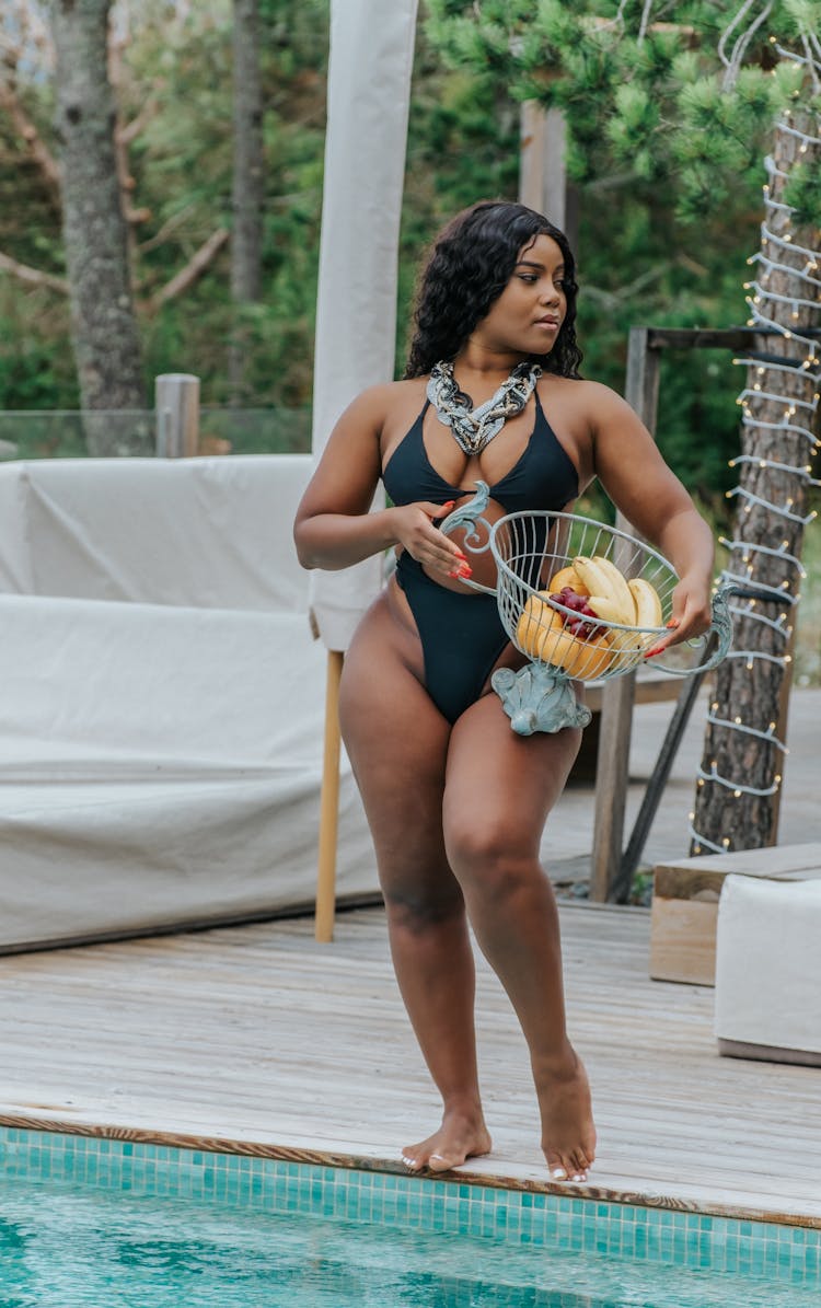 Woman Holding A Fruit Basket By The Pool 