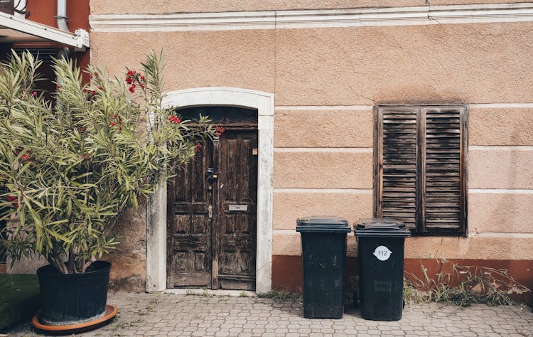 Garbage Bins Beside A Wooden Window