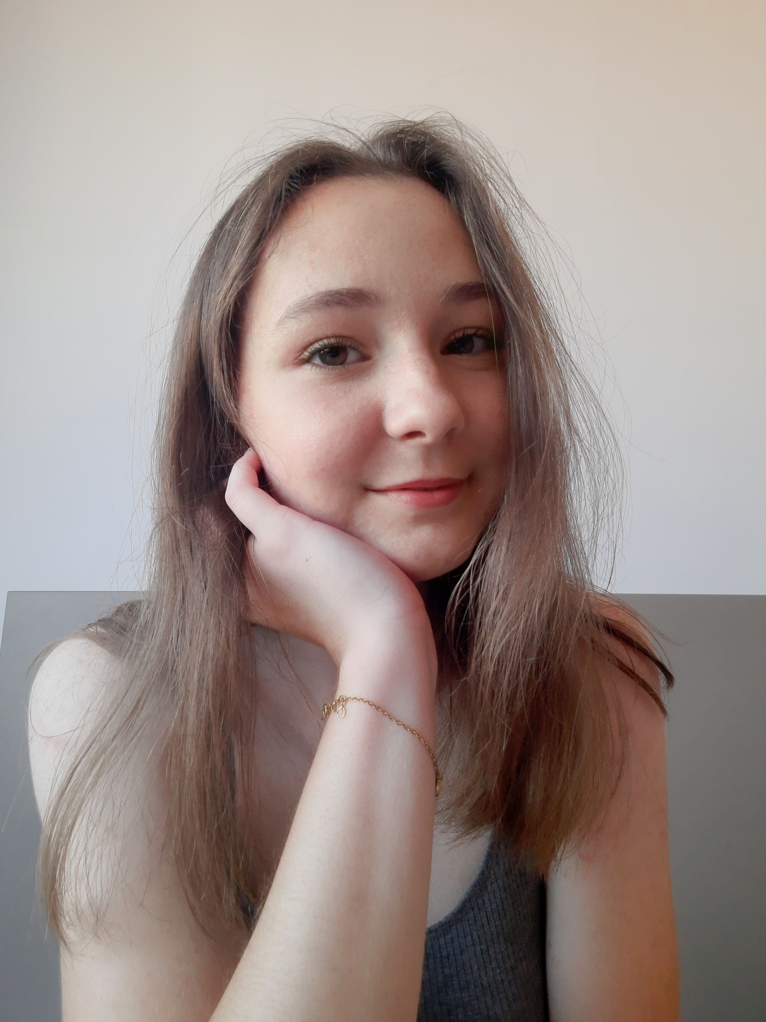 Portrait of a young woman with a casual pose indoors, exuding charm and simplicity.