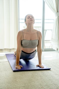 Woman in yoga attire performs upward facing dog indoors, symbolizing fitness and wellness.