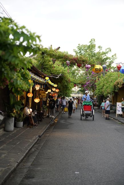 Charming street scene with colorful lanterns and rickshaw on a vibrant Asian street, capturing local culture.
