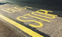 公交车站标记特写，位于城市沥青路上，带有黄线