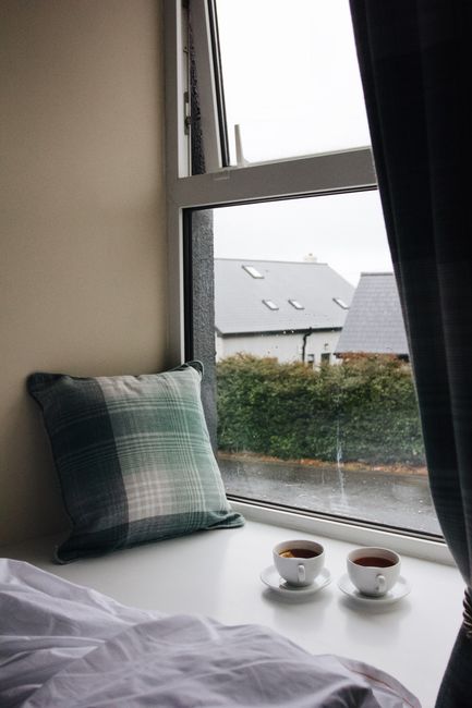 Warm scene of two cups of tea by a window seat in Galway, Ireland, exuding homely comfort.