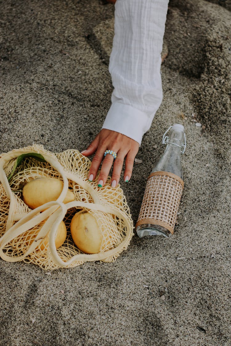 Hand Touching A Net Bag With Fruits