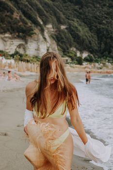 Smiling woman in swimwear walks along a beautiful summer beach.