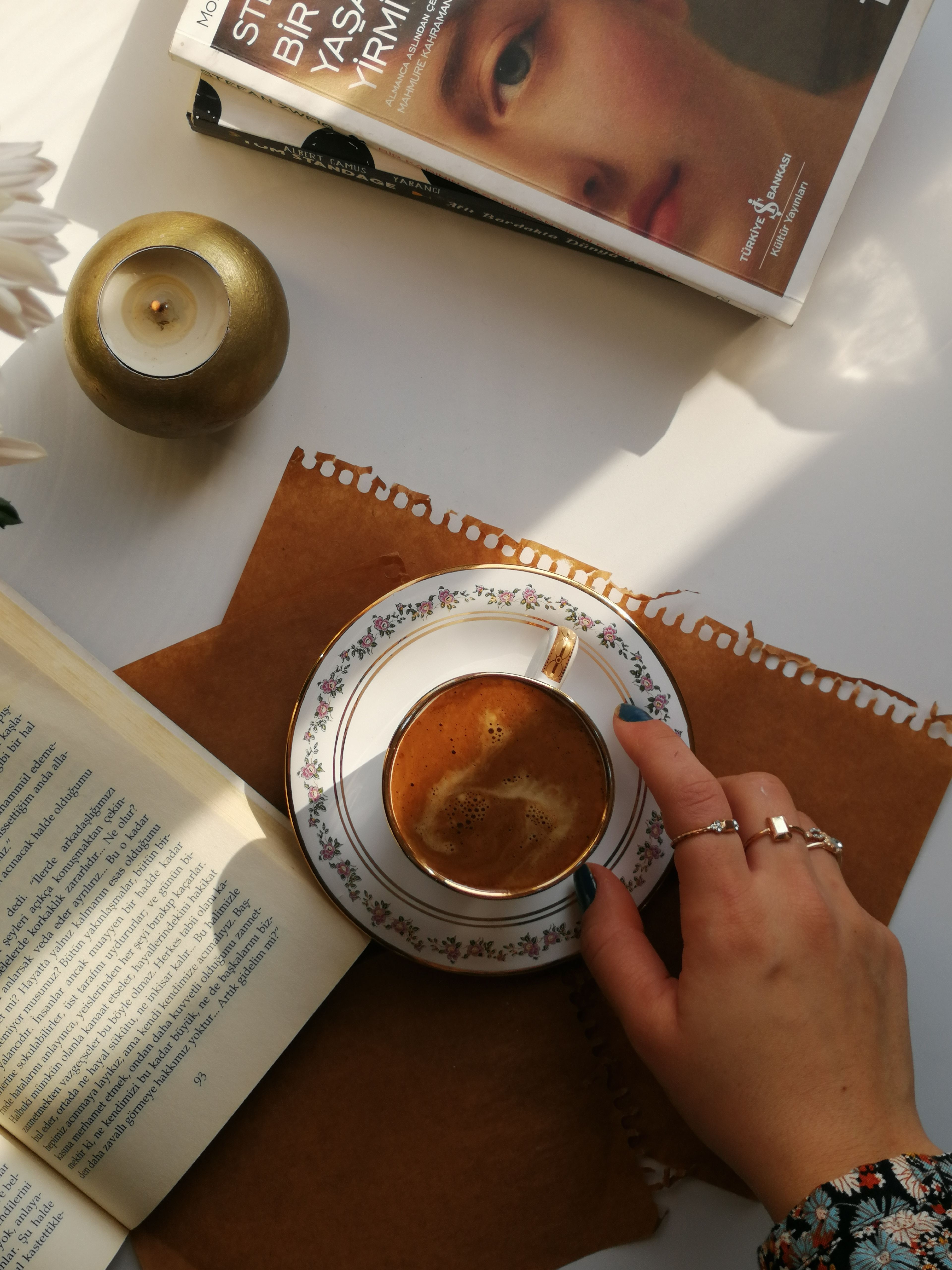 Flat lay of a coffee cup, books, and candle creating a warm atmosphere.