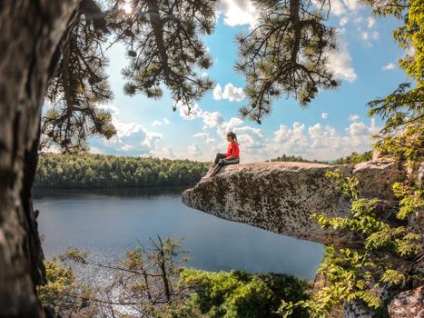 Girl Sitting on Rock Overhang Over Lake