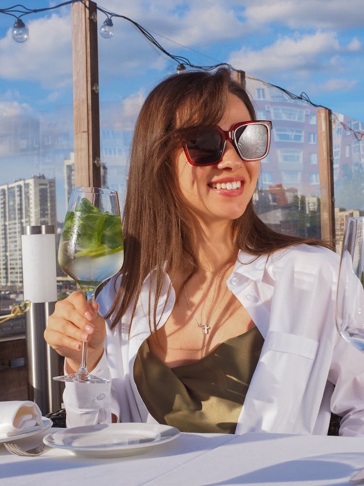 A Woman Smiling While Holding A Glass Of Cocktail