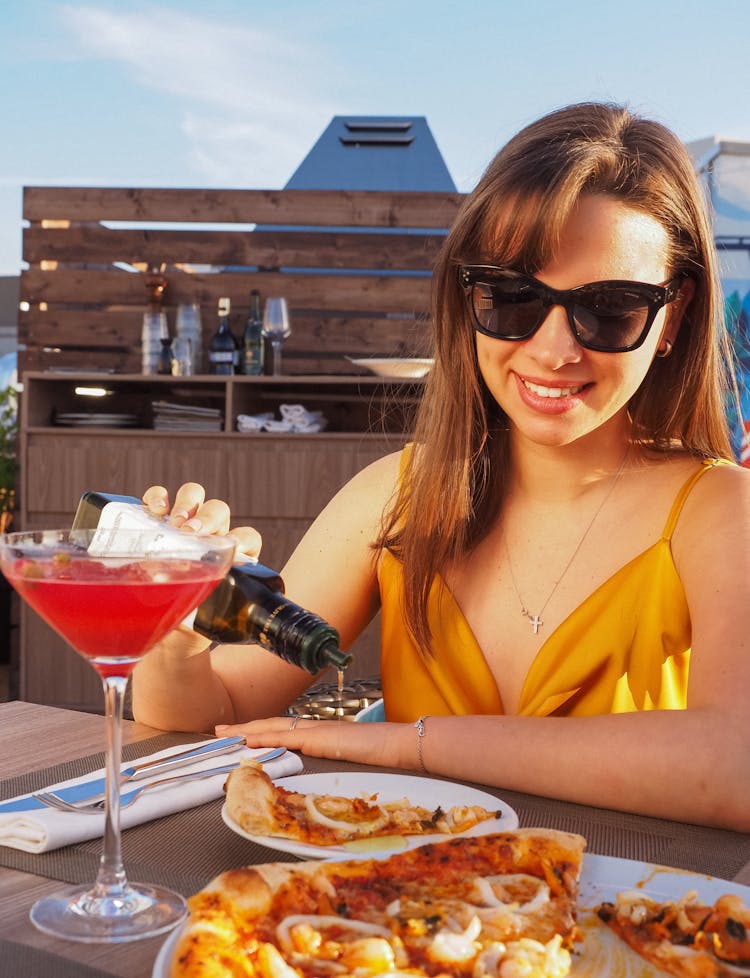 A Woman Pouring Olive Oil On A Pizza