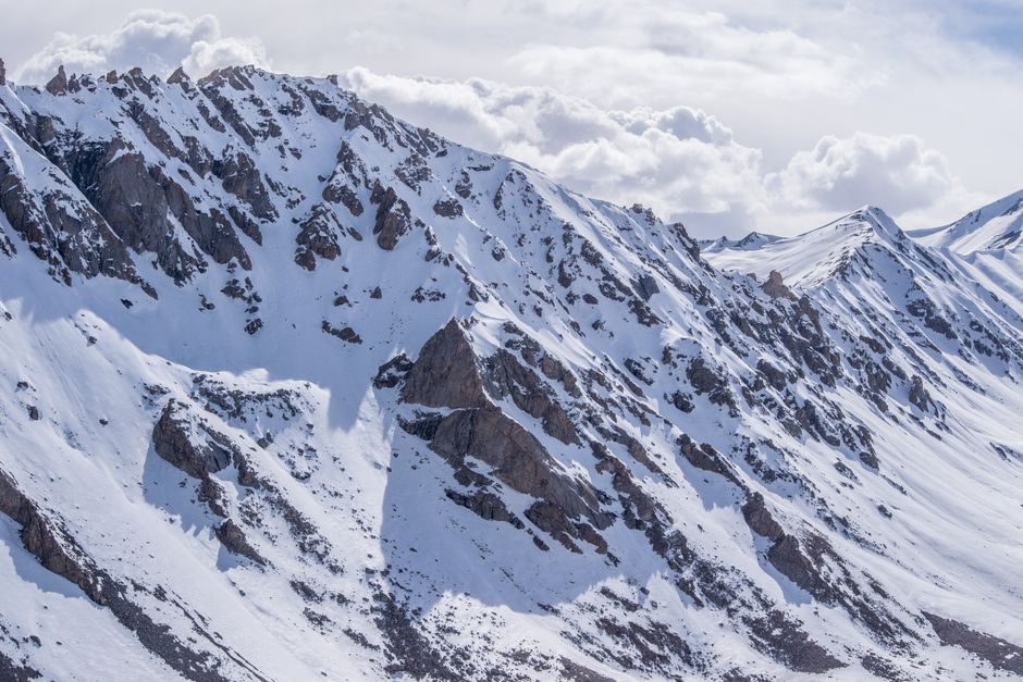 Stunning view of snow-capped mountain peaks under a cloudy sky.