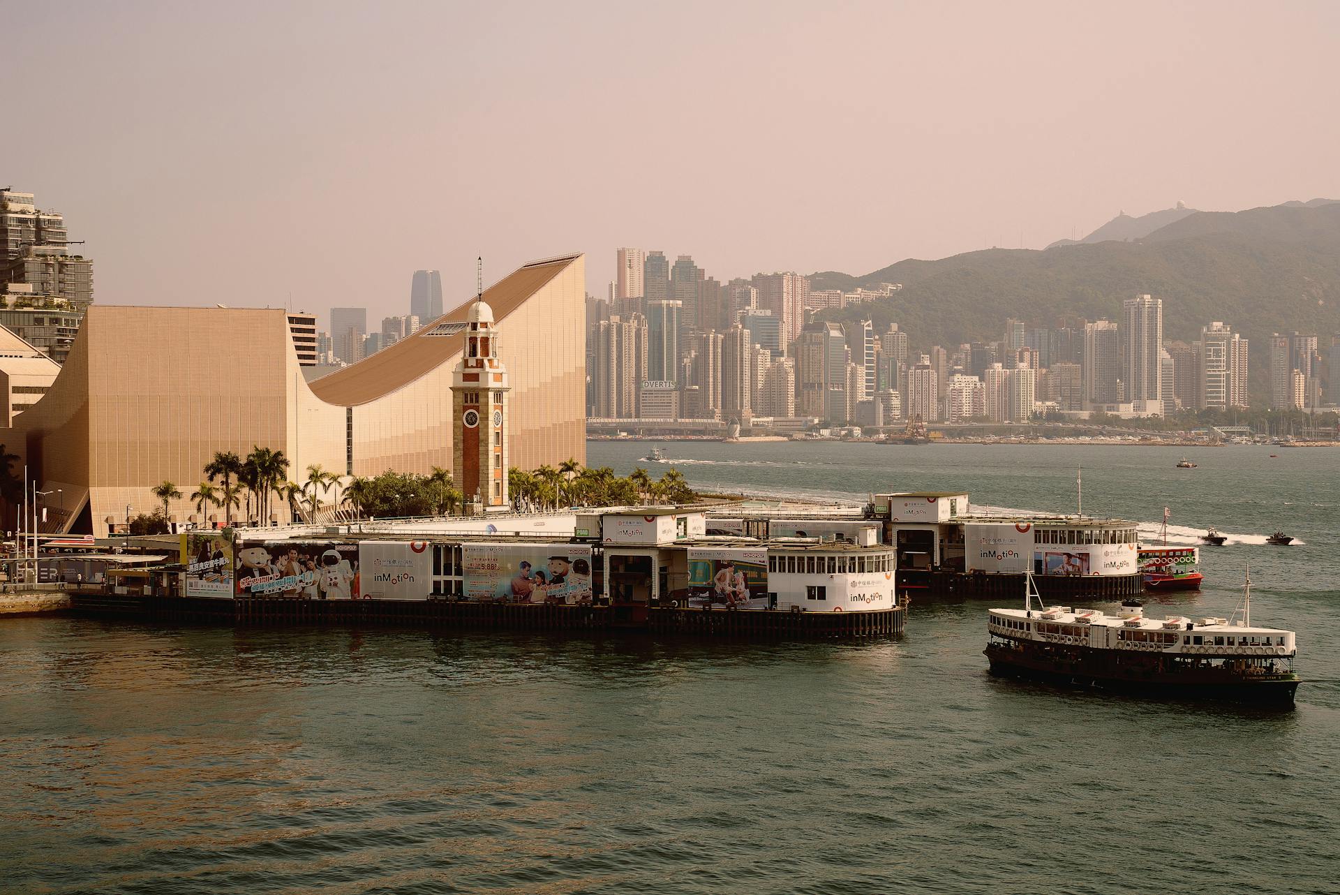 View of Clock Tower and ferry terminal against Hong Kong skyline across Victoria Harbour.