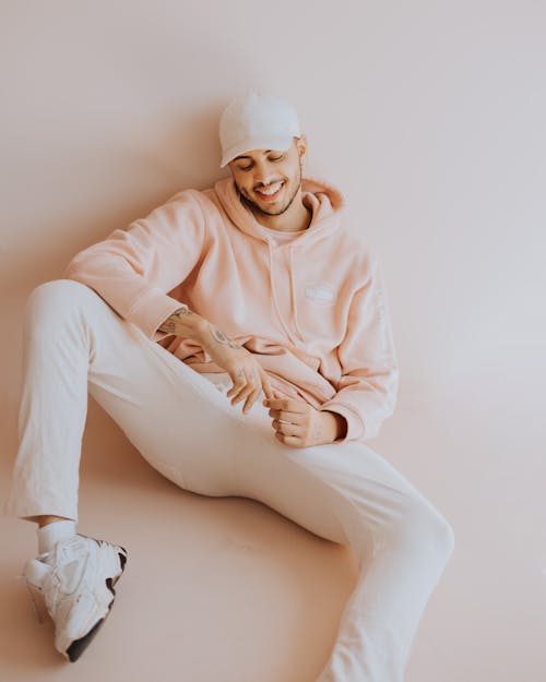 Man in Cap and Hoodie Sitting and Smiling