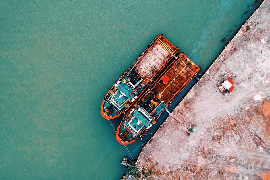 Aerial shot of industrial ships docked at a harbor, showing vivid color contrasts and rustic elements.