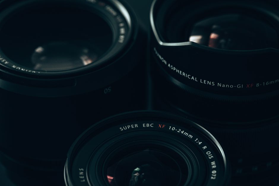 Adaptador de objetiva acoplado a câmera mirrorless ao lado de objetiva DSLR sobre superfície escura