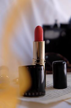 A stylish red lipstick in a classic black case with a blurred background, ideal for beauty themes.