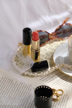 Stylish still life featuring makeup and accessories on a vintage page. Perfect for beauty themes.