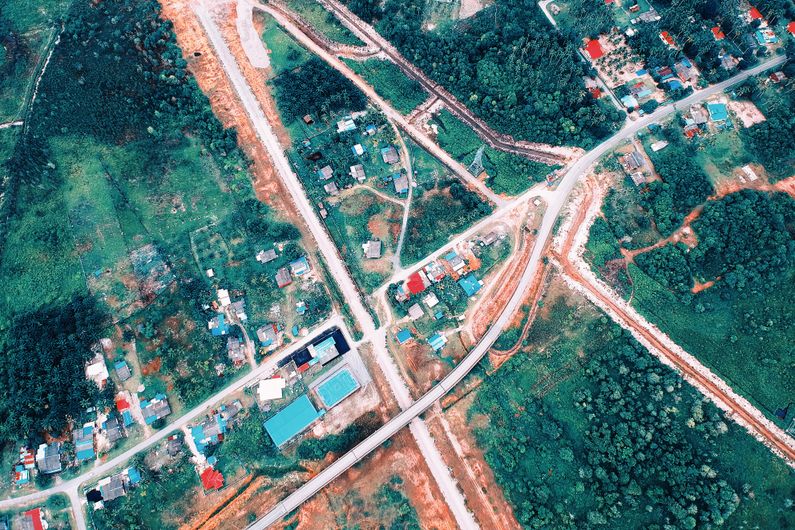 Aerial view of a settlement and road junction surrounded by open green land