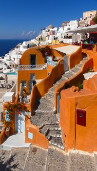 Vibrant orange and white cliffside buildings with stairs in Fira, Santorini.