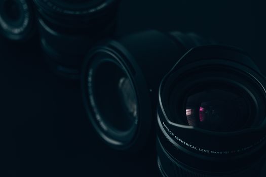 Artistic close-up of a collection of camera lenses in dim lighting, showcasing details and textures.