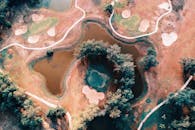 无人机拍摄了一个风景秀丽的高尔夫球场，球场内设有小路和池塘，坐落在一片充满活力的景观之中