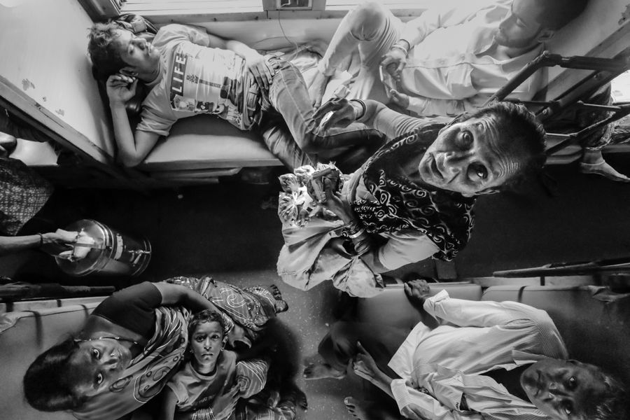 A black and white photo capturing passengers in an Indian train compartment.