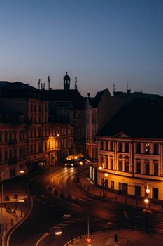 A tranquil European city street at twilight with historic facades and streetlights glowing.