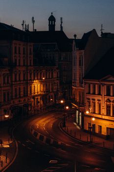 A serene evening view of a historic city street illuminated by warm streetlights, featuring classic architecture.