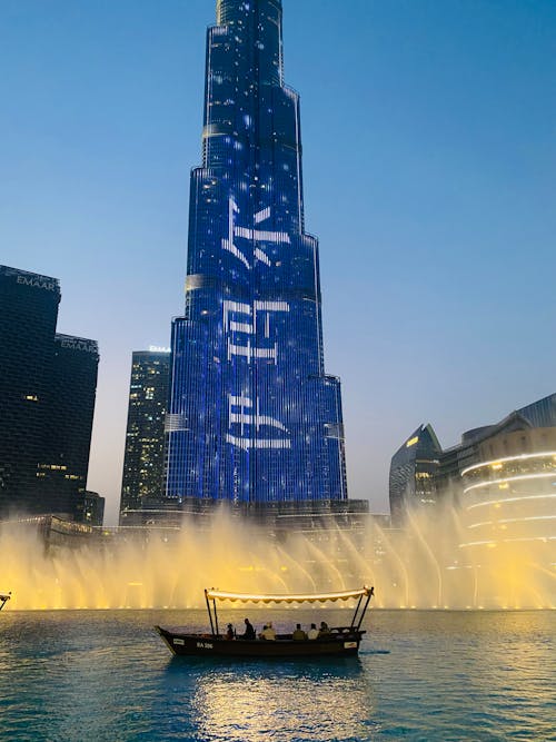 Photo of a the Burj Khalifa Skyscraper, the Fountain and a Boat in Dubai at Night